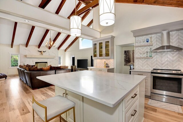 kitchen with pendant lighting, wall chimney exhaust hood, a center island, and electric range