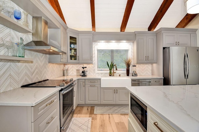 kitchen featuring sink, lofted ceiling with beams, appliances with stainless steel finishes, island exhaust hood, and light stone countertops