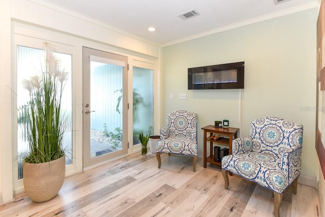 living area with ornamental molding, plenty of natural light, and light hardwood / wood-style flooring