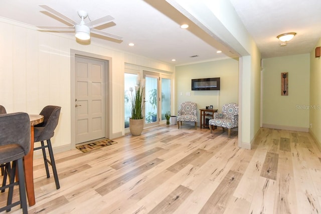 living area with crown molding and light hardwood / wood-style flooring