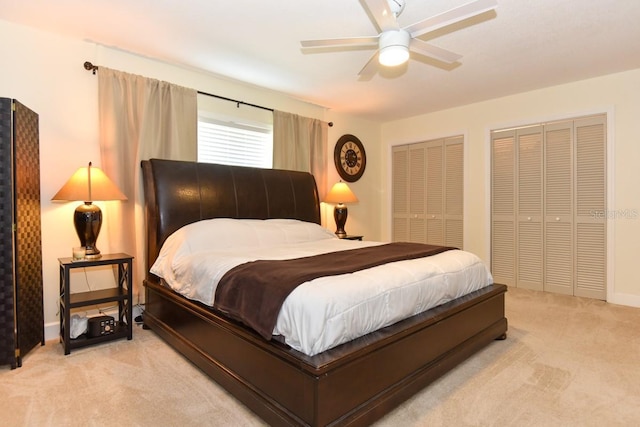 bedroom featuring multiple closets, light colored carpet, and ceiling fan