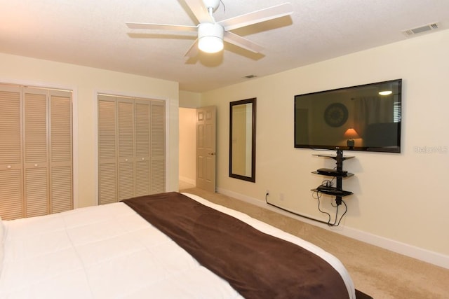 bedroom featuring ceiling fan, carpet flooring, and two closets