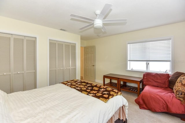 bedroom featuring two closets, carpet floors, and ceiling fan