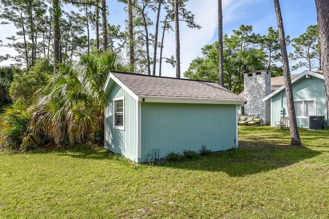 view of outbuilding featuring central AC unit and a lawn