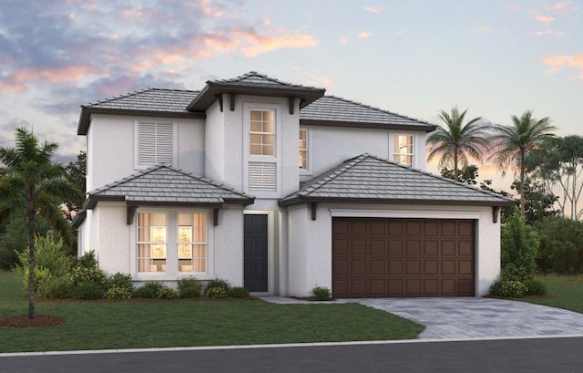 view of front facade with a garage, a tile roof, decorative driveway, a lawn, and stucco siding