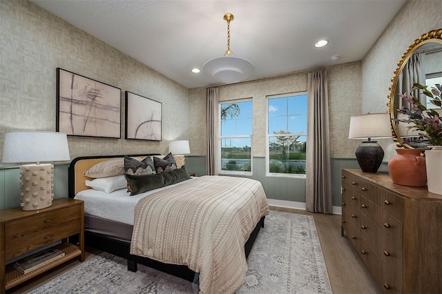 bedroom featuring light wood finished floors, wainscoting, recessed lighting, and wallpapered walls