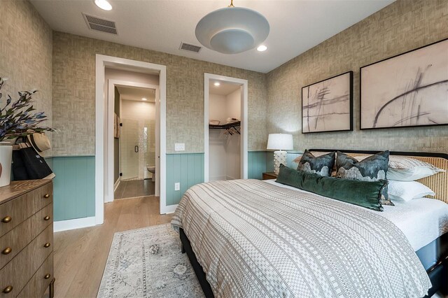 bedroom featuring light wood-type flooring, wainscoting, and visible vents