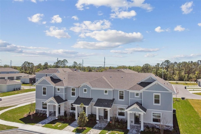 townhome / multi-family property with stone siding and roof with shingles