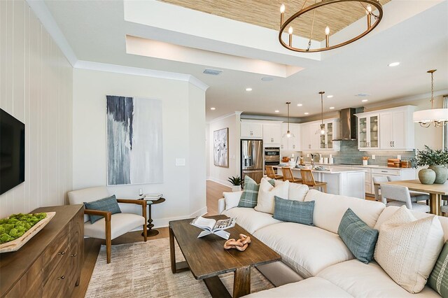 living room featuring ornamental molding, light wood-type flooring, and an inviting chandelier