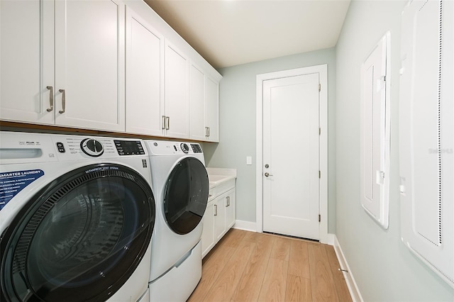 laundry room with washer and clothes dryer, light hardwood / wood-style floors, and cabinets