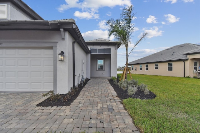 property entrance with a lawn and a garage