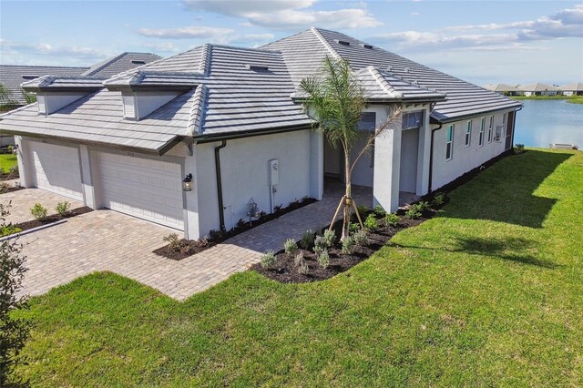 view of home's exterior with a lawn, a water view, and a garage