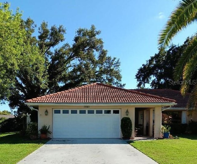 1608 Bob O Link Dr, Venice, FL 34293 - mediterranean / spanish-style home featuring driveway, an attached garage, stucco siding, a front lawn, and a tiled roof