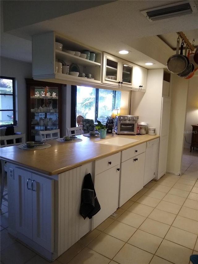 1608 Bob O Link Dr, Venice, FL 34293 - kitchen featuring light tile patterned floors, visible vents, a toaster, glass insert cabinets, and white cabinetry