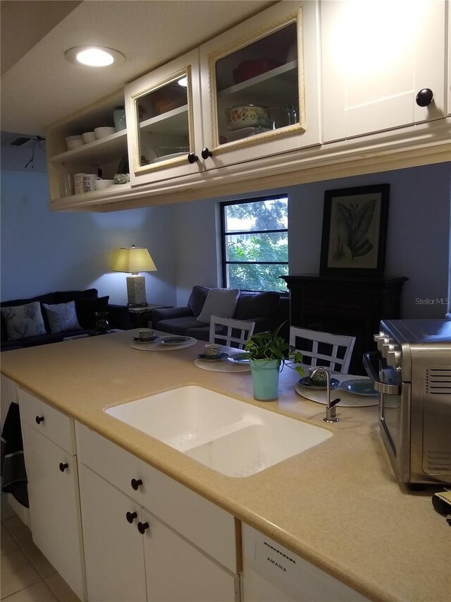 kitchen with white cabinets, dishwasher, light tile patterned flooring, and sink