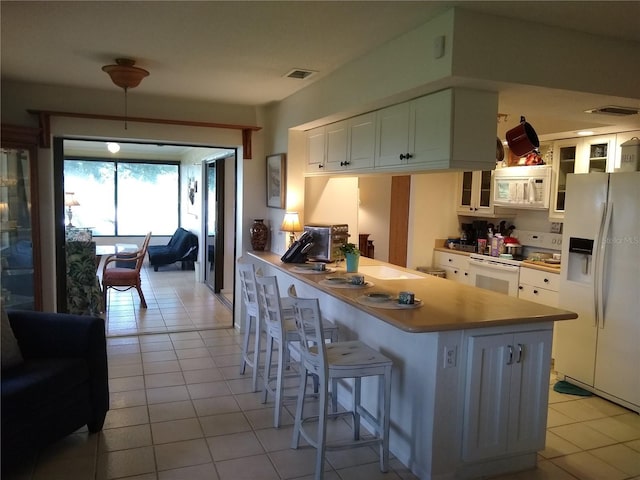 1608 Bob O Link Dr, Venice, FL 34293 - kitchen featuring visible vents, glass insert cabinets, light tile patterned floors, a peninsula, and white appliances