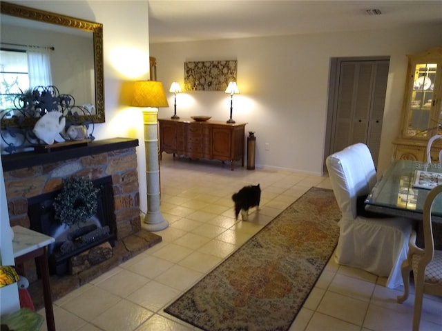 tiled living room featuring a stone fireplace