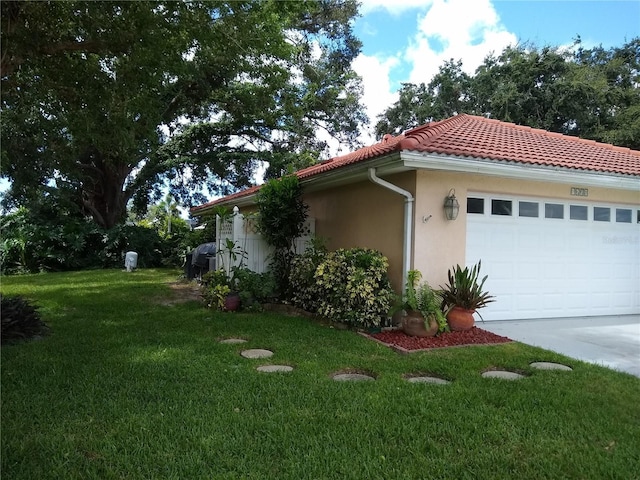 1608 Bob O Link Dr, Venice, FL 34293 - view of side of home featuring a tiled roof, an attached garage, a yard, and stucco siding