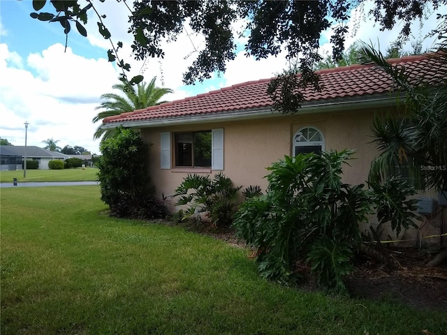 1608 Bob O Link Dr, Venice, FL 34293 - view of side of property featuring stucco siding, a tiled roof, and a yard