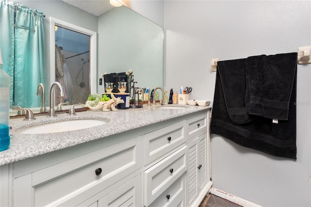 bathroom featuring a shower, double vanity, and a sink