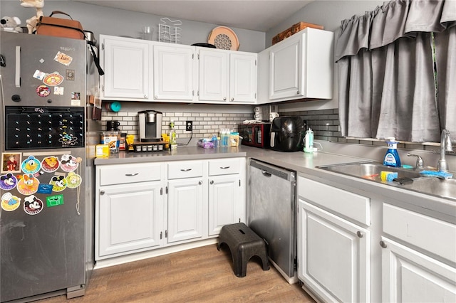 kitchen featuring backsplash, stainless steel appliances, sink, light hardwood / wood-style floors, and white cabinetry