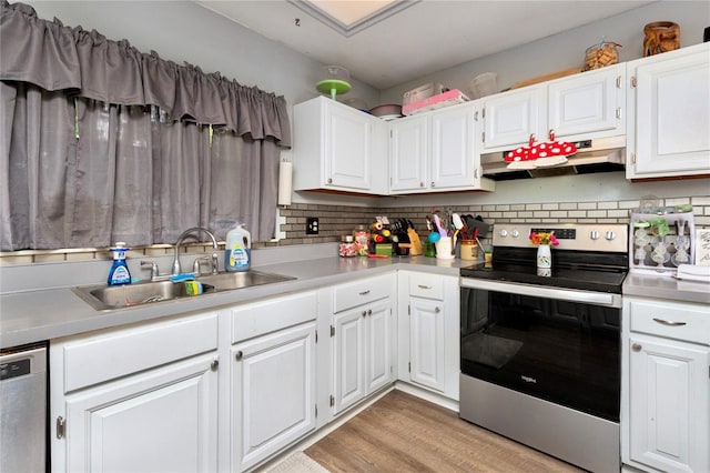 kitchen with under cabinet range hood, appliances with stainless steel finishes, light countertops, and a sink