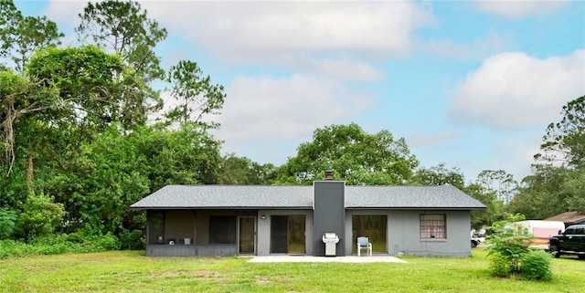 back of property featuring a patio area, a lawn, and a chimney