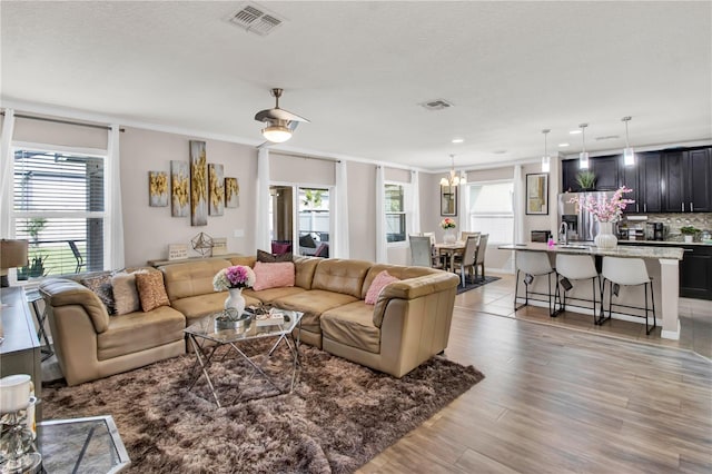 living room featuring a chandelier, a wealth of natural light, sink, and light hardwood / wood-style flooring