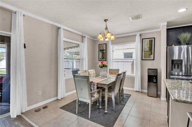 tiled dining room with a textured ceiling, a notable chandelier, and ornamental molding