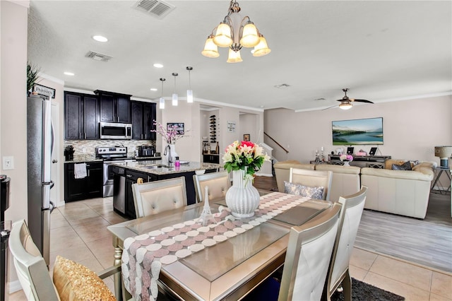 dining space featuring ceiling fan with notable chandelier, light hardwood / wood-style flooring, sink, and crown molding