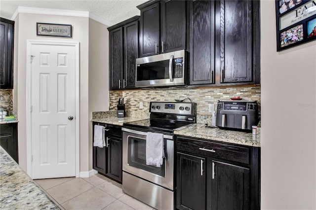 kitchen featuring light stone counters, ornamental molding, light tile patterned flooring, appliances with stainless steel finishes, and a textured ceiling