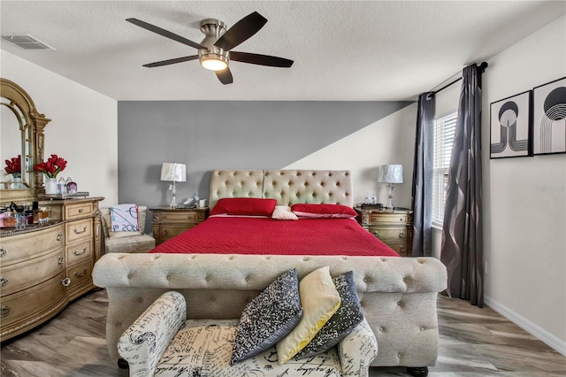 bedroom featuring hardwood / wood-style floors, ceiling fan, and a textured ceiling