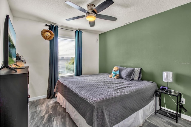 bedroom with a textured ceiling, hardwood / wood-style flooring, and ceiling fan