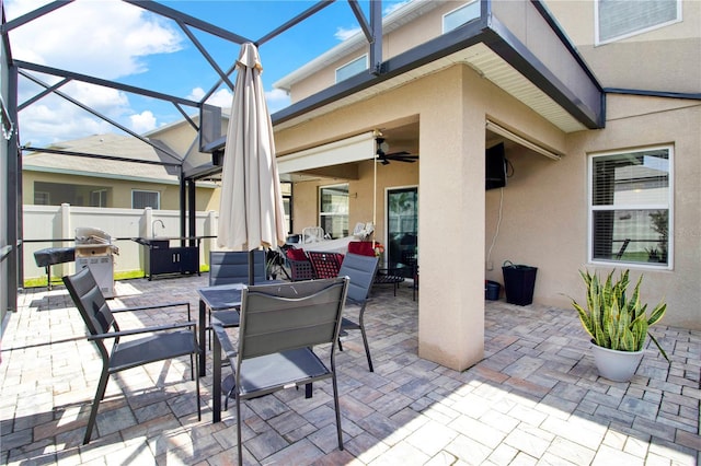 view of patio featuring ceiling fan, glass enclosure, and grilling area