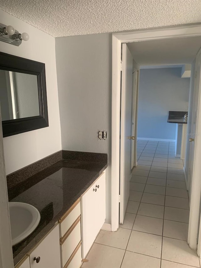 bathroom with a textured ceiling, vanity, and tile patterned flooring