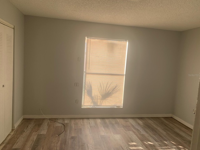 empty room featuring a textured ceiling and hardwood / wood-style flooring