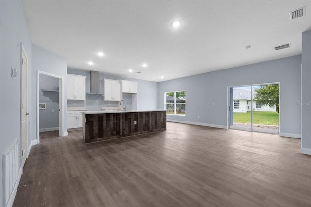 kitchen featuring an island with sink, wall chimney exhaust hood, and dark hardwood / wood-style floors