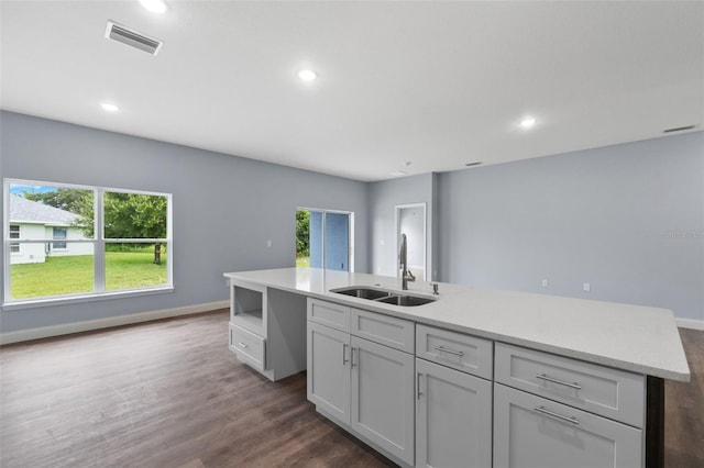 kitchen with a center island, wood-type flooring, sink, and light stone countertops