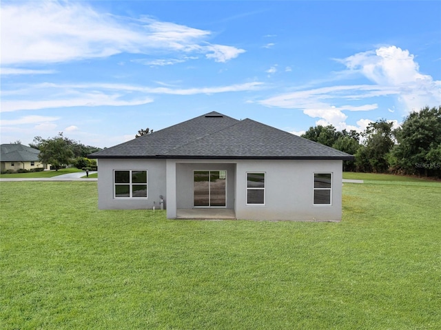 rear view of property with a shingled roof, a lawn, and stucco siding