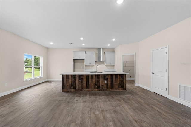 kitchen with sink, a kitchen island with sink, wall chimney exhaust hood, and wood-type flooring