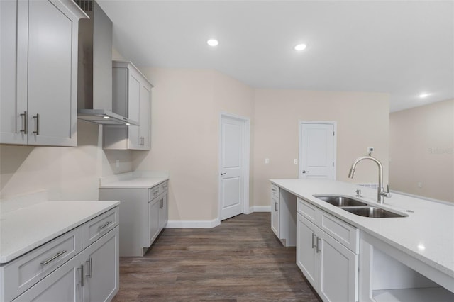 kitchen featuring dark wood finished floors, recessed lighting, light countertops, a sink, and wall chimney exhaust hood