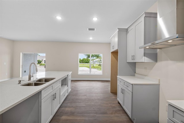 kitchen with sink, gray cabinetry, dark hardwood / wood-style flooring, and wall chimney exhaust hood