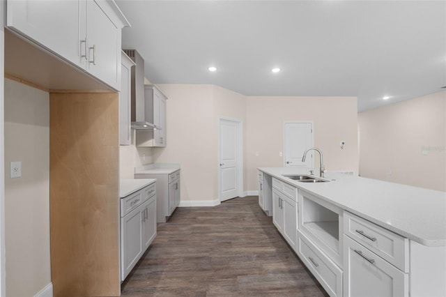 kitchen featuring sink, dark wood-type flooring, wall chimney range hood, and white cabinets