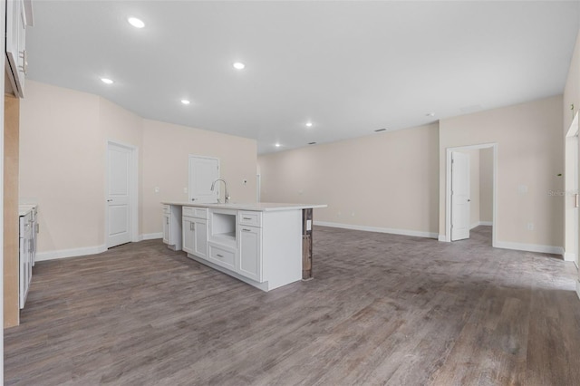 kitchen with a kitchen island with sink, hardwood / wood-style flooring, sink, and white cabinets