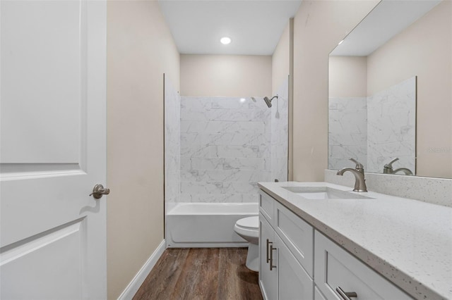 bathroom with toilet, vanity, shower / tub combination, wood finished floors, and baseboards