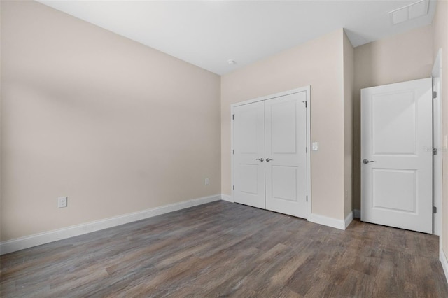 unfurnished bedroom with visible vents, a closet, baseboards, and wood finished floors