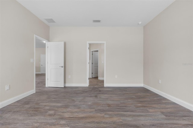 unfurnished bedroom with visible vents, baseboards, and dark wood-type flooring