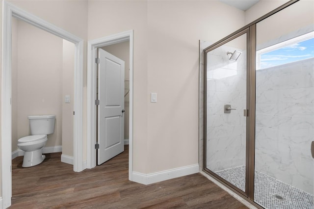 bathroom with toilet, a shower with door, and wood-type flooring