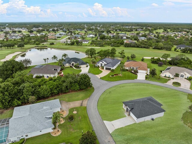 drone / aerial view featuring golf course view, a water view, and a residential view