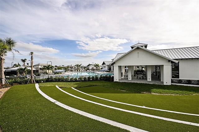 view of property's community featuring a patio area, a swimming pool, and a lawn